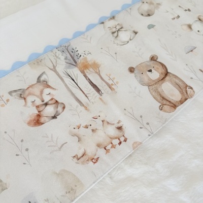 Cobertor infantil com padrão de animais em tons pastel e borda azul ondulada