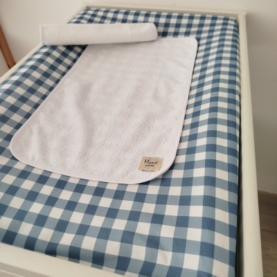 Tapete de trocador azul e branco com toalha branca com etiqueta Mamã pintinha
