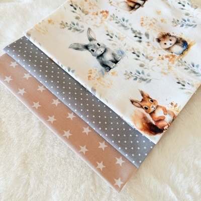 Tecidos dobrados com padrões de animais, bolinhas e estrelas.