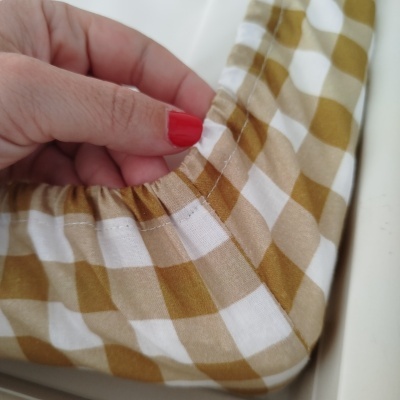 Mão segurando tecido xadrez castanho e branco elástico