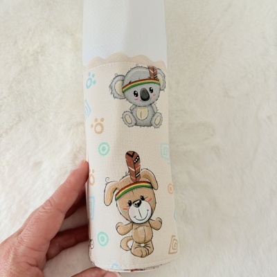Manta branca com desenhos infantis de coala e cachorro sob fundo bege.