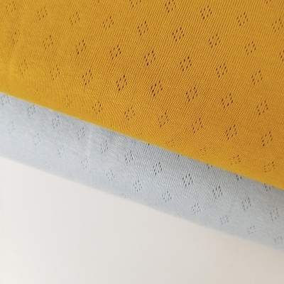 Tecido de malha com padrão perfurado em amarelo mostarda e cinza claro