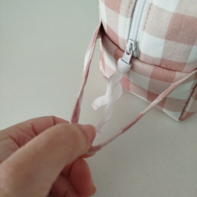 Mochila pequena rosa e branca com padrão de quadrados e fecho branco