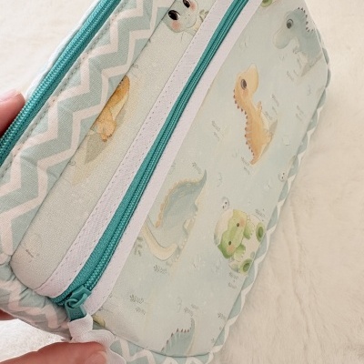 Estojo ou bolsa de tecido com padrão de dinossauros e zíper verde-azulado