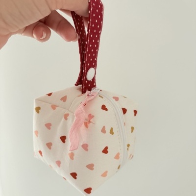Bolsa pequena com padrão de corações e alça vermelha de bolinhas.