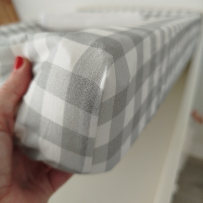 Tecido xadrez cinza e branco segurado por mão com unha vermelha