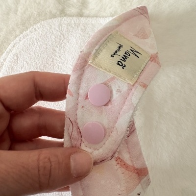 Babete branco felpudo com parte rosa estampada e botões de pressão