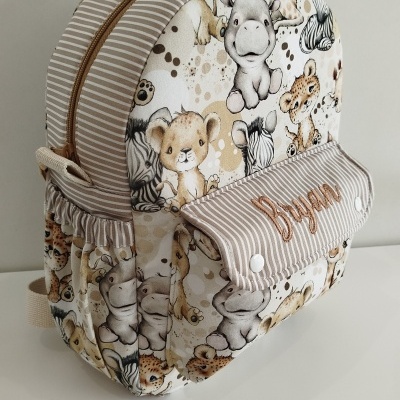 Mochila infantil bege e branca com padrão de animais e texto 'Bryan' bordado.