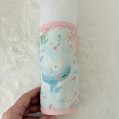 Fralda ou pano branco com padrão de baleia azul e peixes cor-de-rosa com acabamento rosa