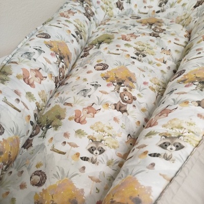 Almofada infantil estampada com desenhos de animais e natureza.