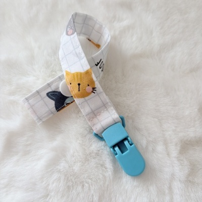 Clip azul com fita estampada com gatos sobre tecido felpudo branco