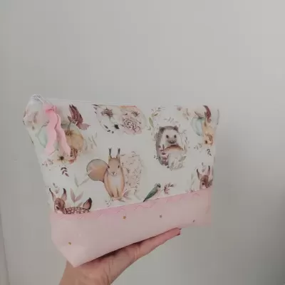 Bolsa ou necessaire tecido com padrão animal pastel e fundo rosa com estrelas.