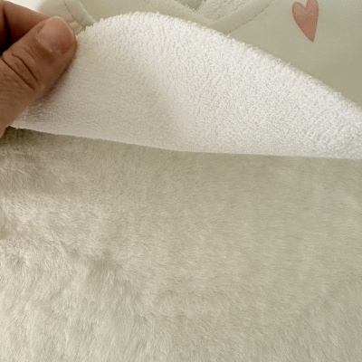 Tecido branco felpudo com interior de toalha e padrão de coração rosa.