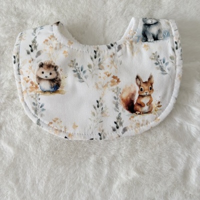 Babete para bebé branco com estampado de animais e folhas em tons suaves