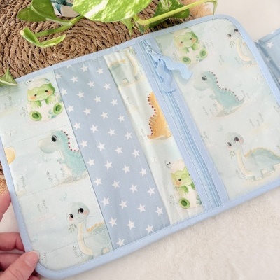 Organizador em tecido azul com estampado de estrelas e dinossauros coloridos