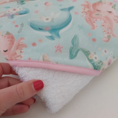 Toalha infantil com padrão de animais marinhos em tons rosa e azul e borda rosa