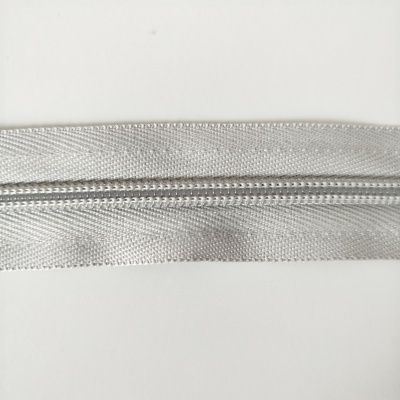 Fecho éclair de nylon cinzento claro com dentes pequenos.
