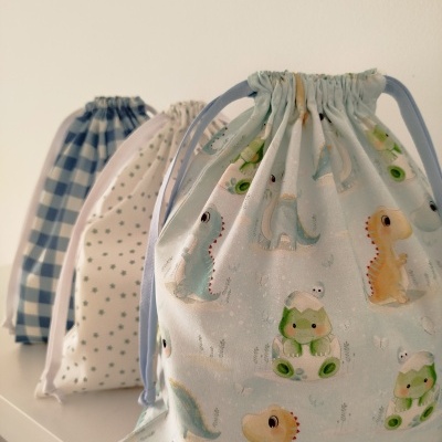 Três saquinhos de tecido com diferentes padrões coloridos sentados numa superfície branca