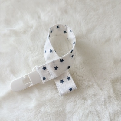 Fita branca com estrelas pretas e clipe branco no fundo felpudo creme
