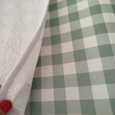 Colchão de berço com capa protetora branca e padrão xadrez verde e branco no tecido exterior