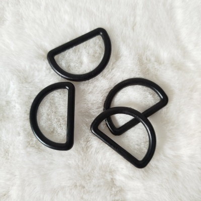 Quatro argolas plásticas pretas em forma de meia-lua sobre fundo branco felpudo