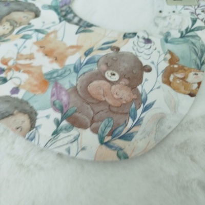 Babete redondo com padrão de animais desenhados em tons pastel