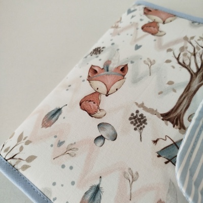 tecido estampado com raposas e elementos da natureza em tons suaves e acabamento azul-claro