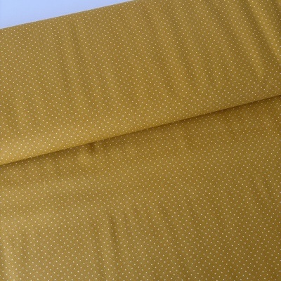 Tecido amarelo mostarda com pequenos pontos brancos dobrado