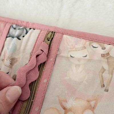 Tecido com padrão de animais pastel e fecho cor-de-rosa