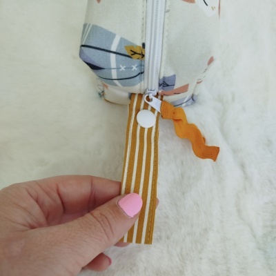 Estojo com padrão geométrico em tons claros e fecho de correr branco