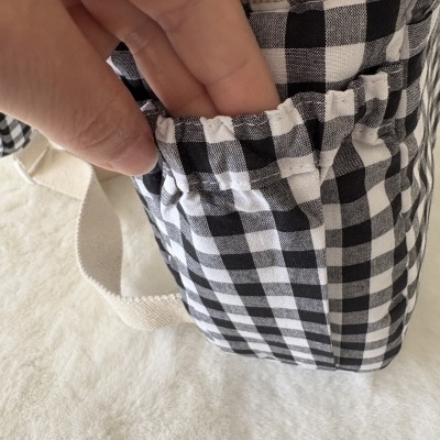 Mala de tecido xadrez preto e branco com bolso elástico e alça bege