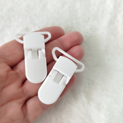 Dois clipes brancos de plástico para roupa na mão, fundo felpudo branco