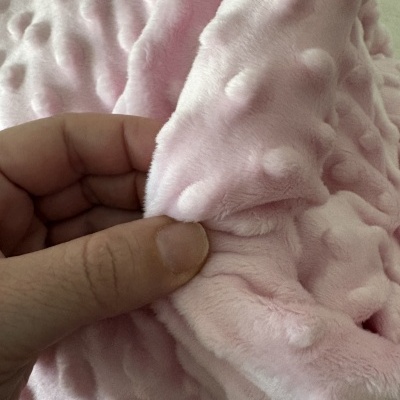 Pano rosa claro macio com texturas em relevo segurado por mão