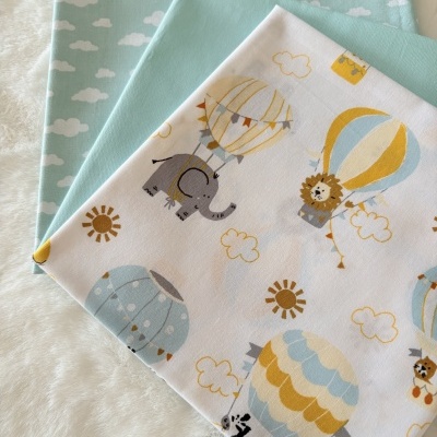 Três tecidos de algodão dobrados com padrões infantis e cores suaves