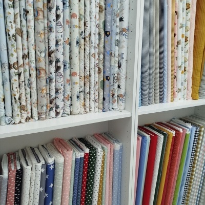 Tecidos variados dobrados em prateleiras com padrões coloridos e texturas diferentes