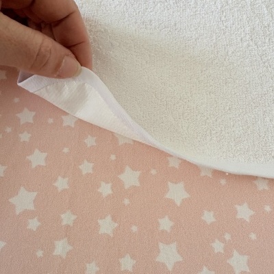 Pano branco com textura felpuda em cima de tecido rosa com estrelas brancas