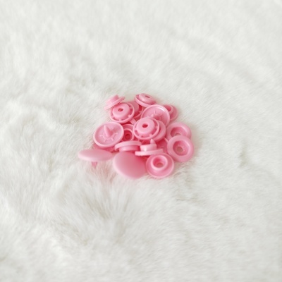 Botões de pressão em plástico rosa num fundo branco macio.