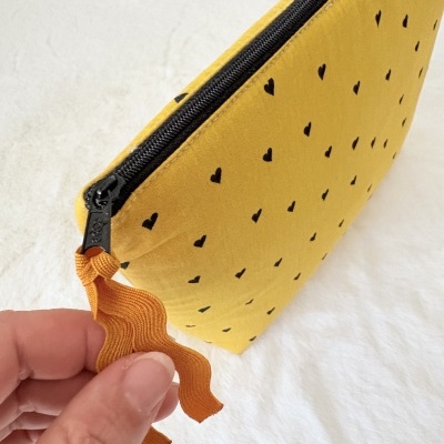 Estojo amarelo com corações pretos e fecho com puxador laranja