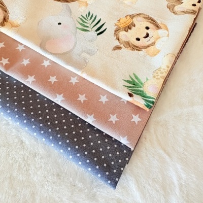 Tecidos dobrados com padrões de animais, estrelas e pontos sobre superfície branca peluda