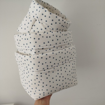 Cobertor branco com estrelas azuis dobrado e segurado por mão