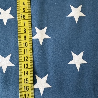 Tecido azul com estrelas brancas e fita métrica amarela sobre ele