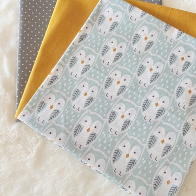 Três tecidos dobrados com padrões diferentes sobre fundo branco.