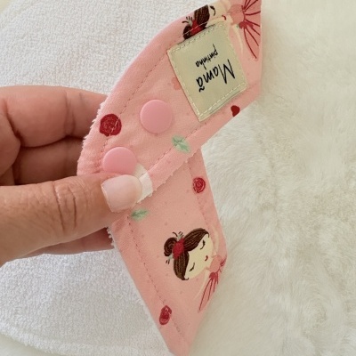 absorvente de tecido rosa com ilustração e botões de pressão