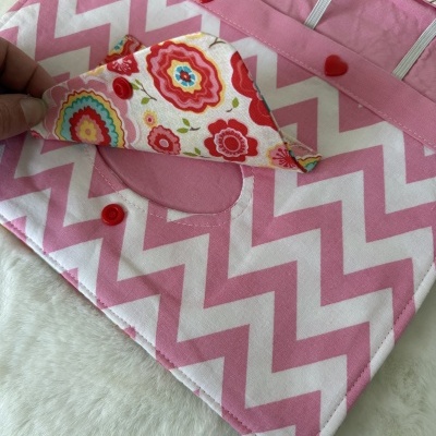 Estojo rosa com padrão chevron branco e interior floral colorido com botões vermelhos