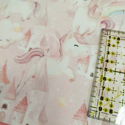 Tecido rosa com padrão de unicórnios e castelos, régua para escala ao lado