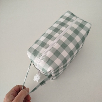 Necessaire quadriculada verde e branca com zipper branco e alça com pendente branco em forma de flor