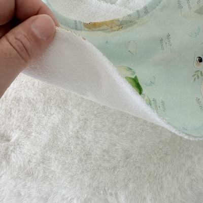 Babete azul claro com padrão infantil e interior branco felpudo