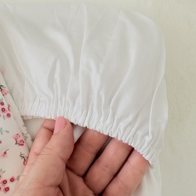 tecido branco com elástico segurado por mão com unhas rosas