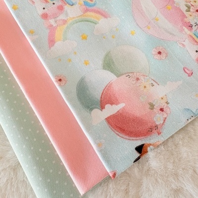 Três tecidos coloridos, estampado de balões e unicórnio, liso rosa e bolinhas brancas em verde-água.
