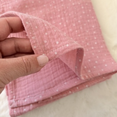 Pano rosa com bolinhas brancas segurado por mão sobre superfície branca